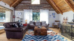 A cozy living room with leather sofas, a coffee table, and a patterned rug. - Cabin at the Forest Edge | Hot tub, pet friendly (Packwood)