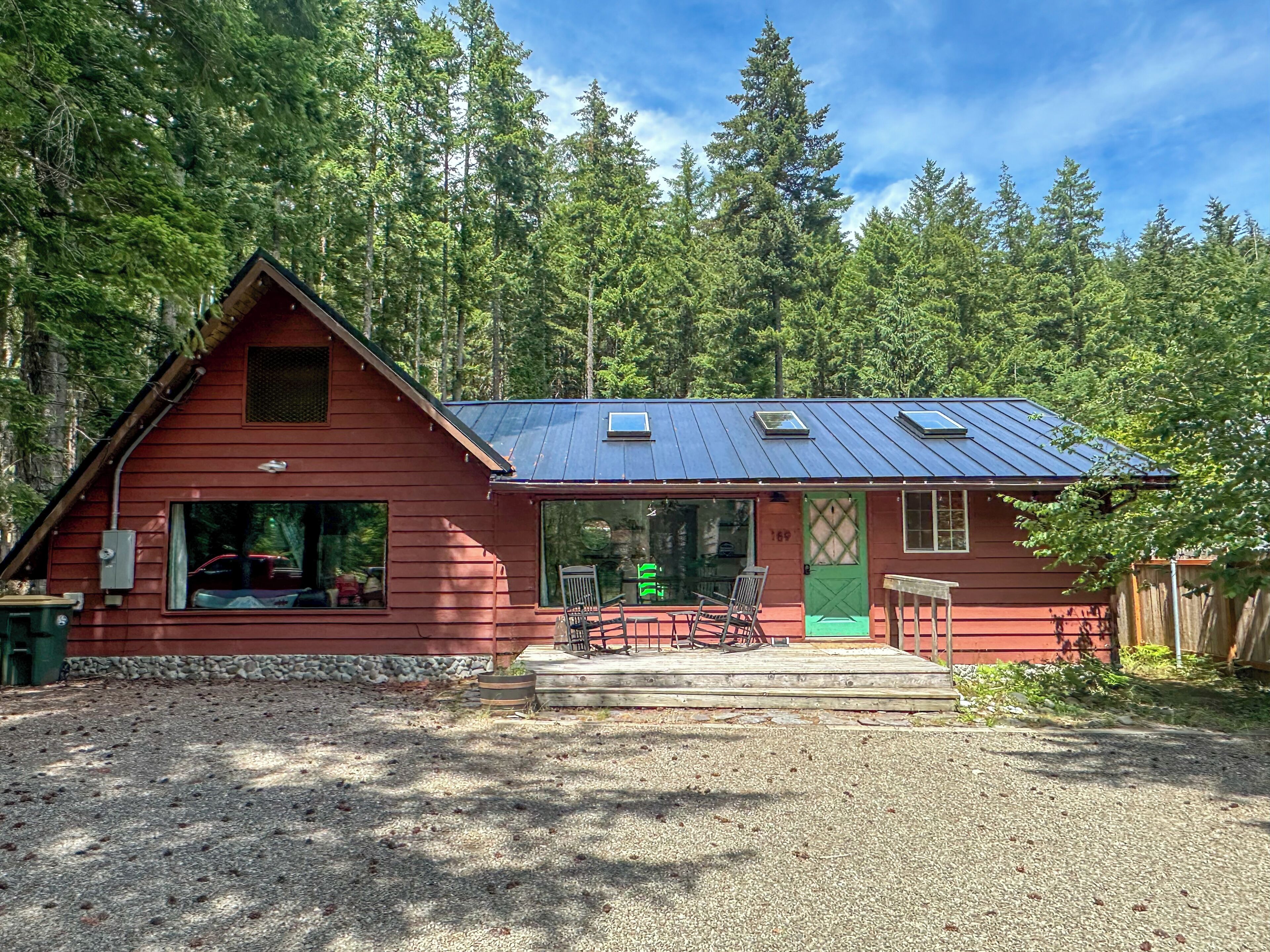 A red cabin with a metal roof, large windows, and a green door.