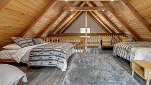 A cozy attic bedroom with two beds, a wooden ceiling, and a fluffy rug. - Hygee Haus | Hot Tub, Wifi, Wood stove (Packwood)