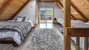 A cozy attic bedroom with two beds, a fluffy rug, and a wooden ceiling. - Hygee Haus | Hot Tub, Wifi, Wood stove (Packwood)
