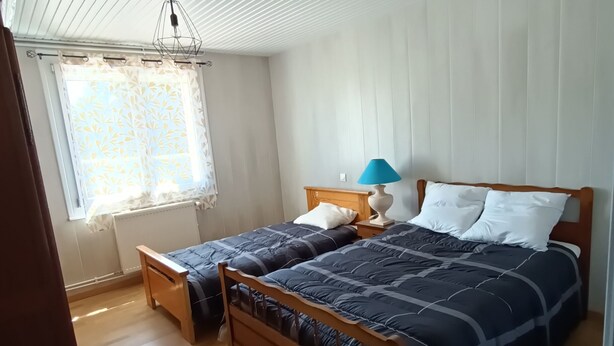 Une chambre à coucher avec deux lits en bois, une fenêtre ornée de rideaux à motifs et un plafond à motifs géométriques.