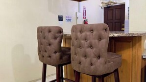 Een keuken met twee bekleden barstoelen, houten kasten en een marmeren vloer.