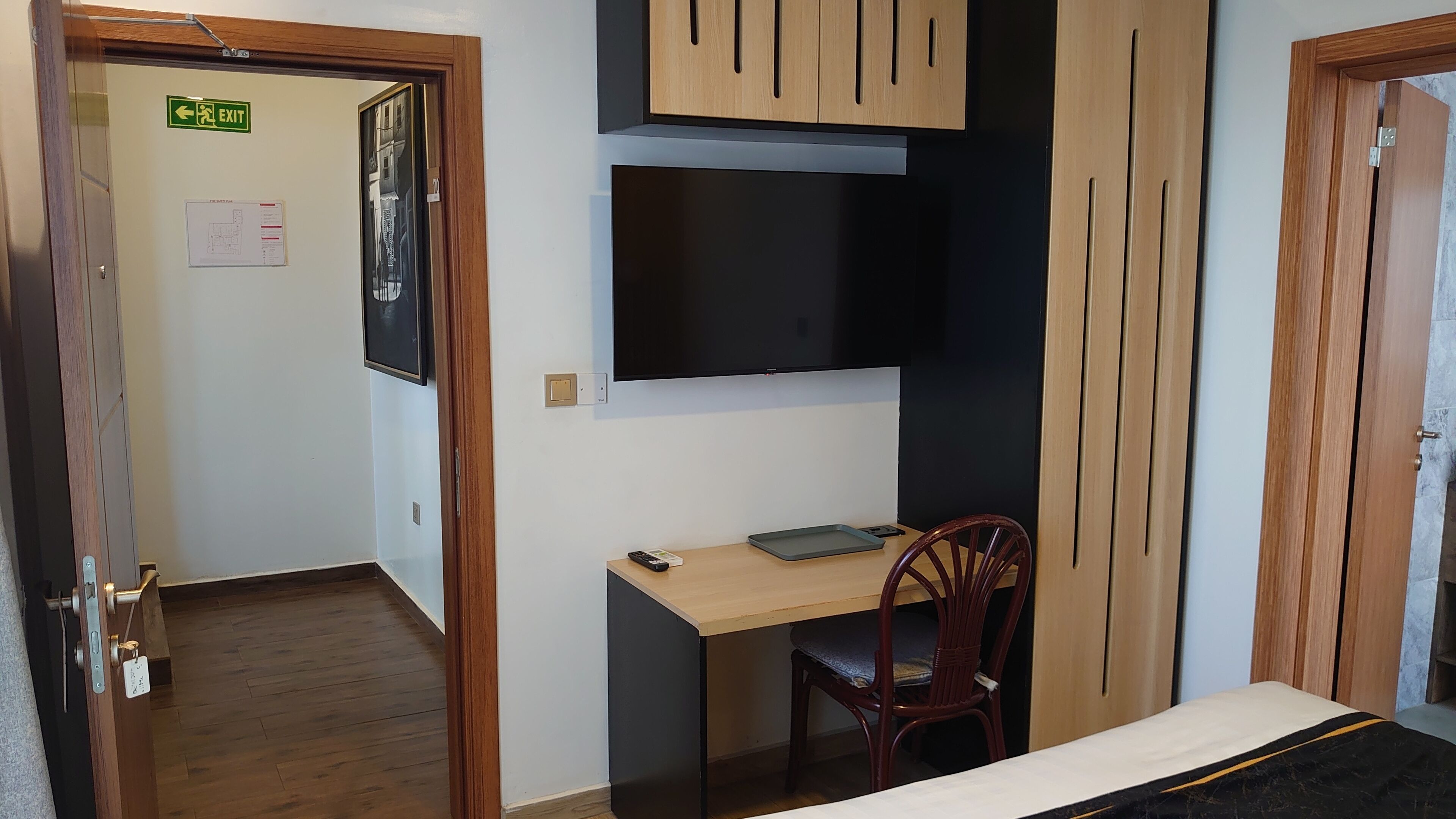 A bedroom with a bed, a desk, a chair, and a TV.