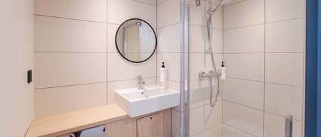 A modern bathroom with a sink, mirror, and shower.