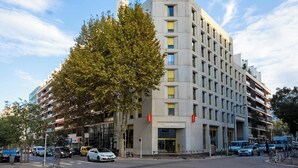 A modern building with a sign reading 'easyHotel,' featuring a prominent entrance, multiple floors, and a large tree in front. - easyHotel Marseille Euromed (Marseille)