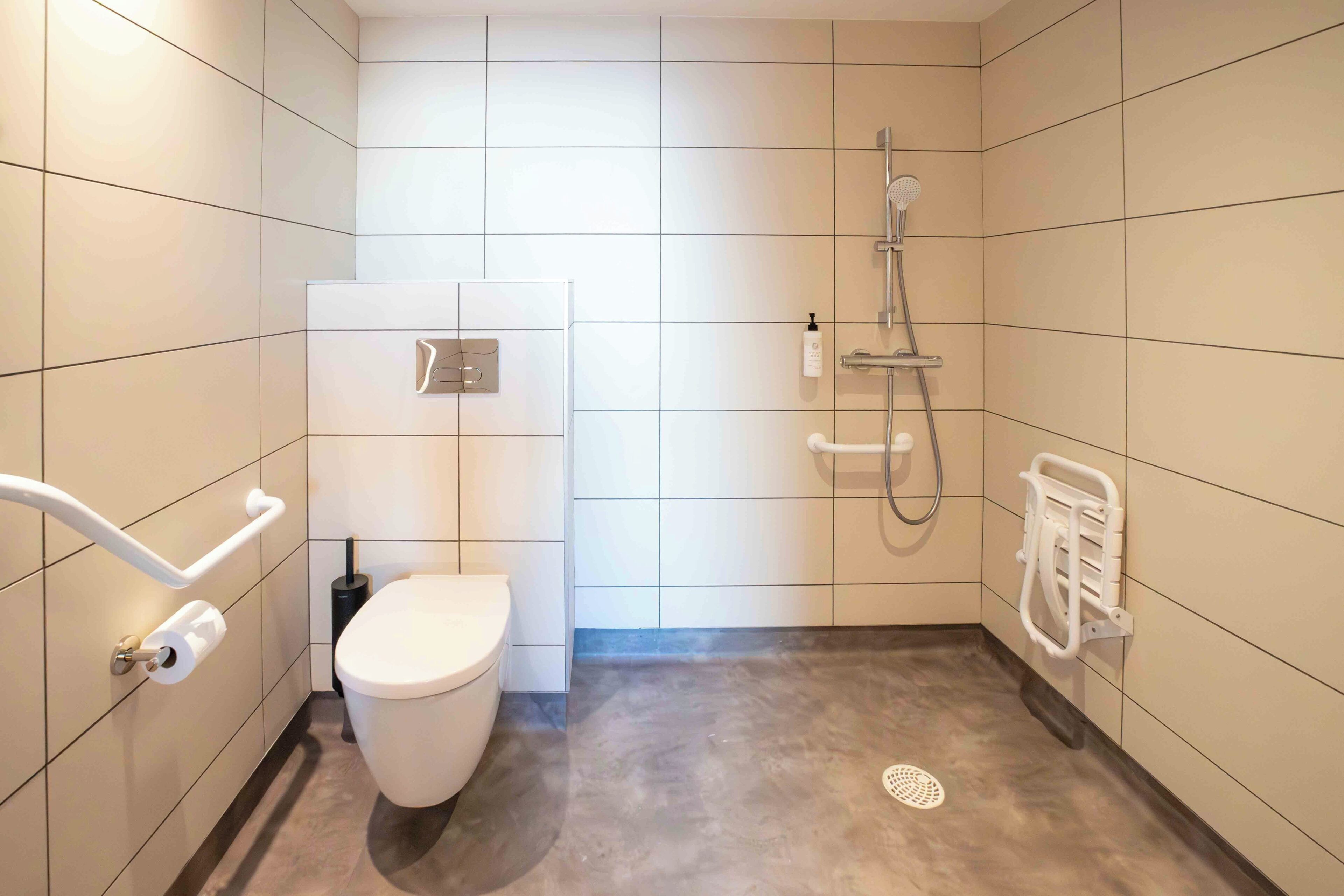 A modern bathroom with a toilet, a shower, and a hand dryer.