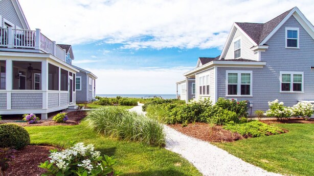 Un área residencial costera con dos casas, un sendero y vistas al mar.