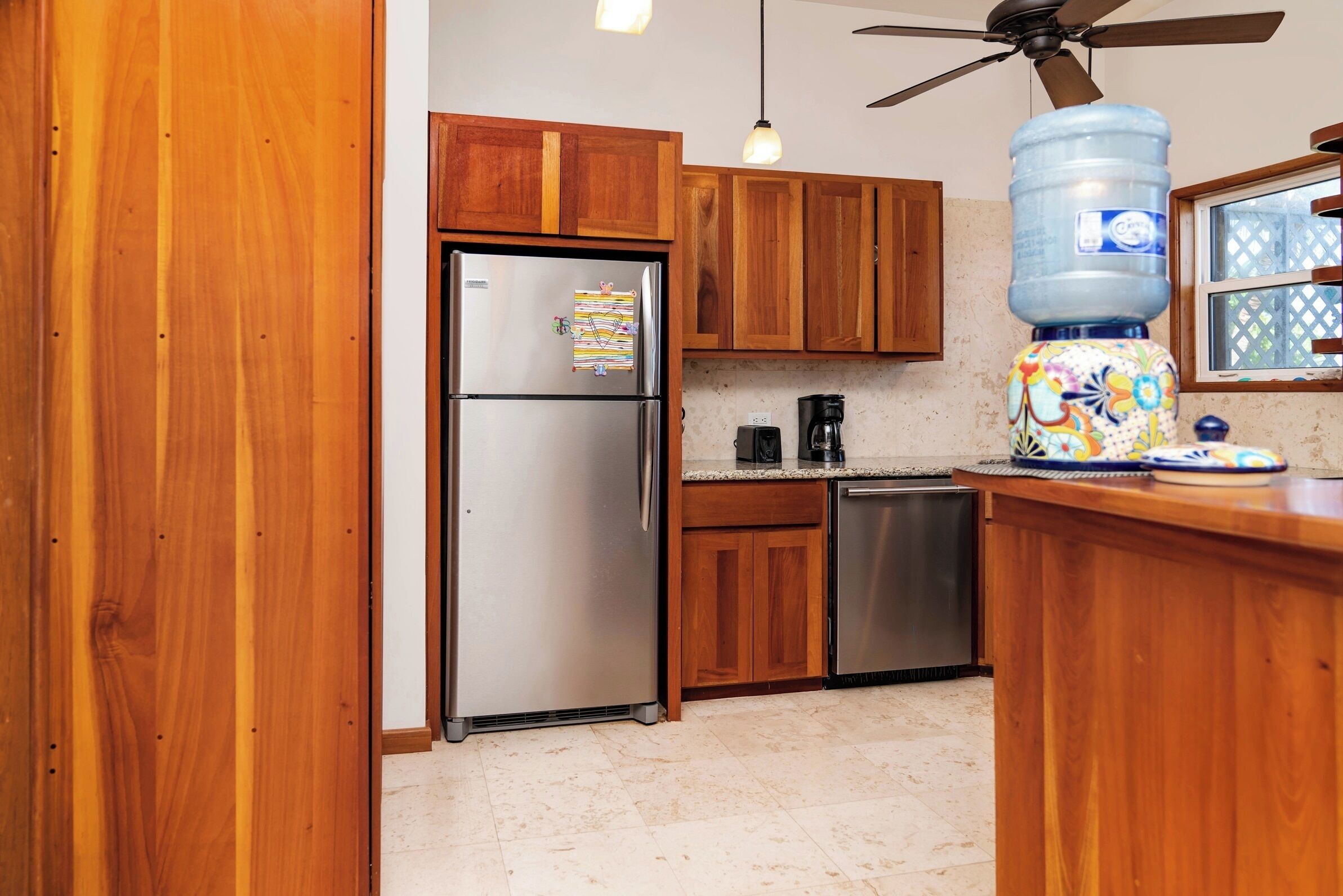 A kitchen with wooden cabinets, a stainless steel refrigerator, a water dispenser, and a coffee maker.