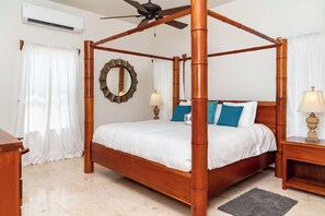 Un lit à baldaquin avec un cadre en bois, un ventilateur de plafond et un climatiseur fixé au mur.