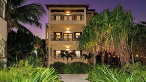 A multi-story hotel with balconies, surrounded by lush tropical vegetation. - Tropical Paradise Awaits: Luxe 2BR Condo in Ambergris Caye! (San Pedro Town)