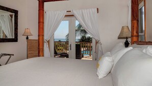 Een slaapkamer met een groot bed, uitzicht op het zwembad en een balkon met uitzicht op de oceaan.