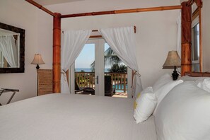 A bedroom with a large bed, a view of the pool, and a balcony with a view of the ocean.