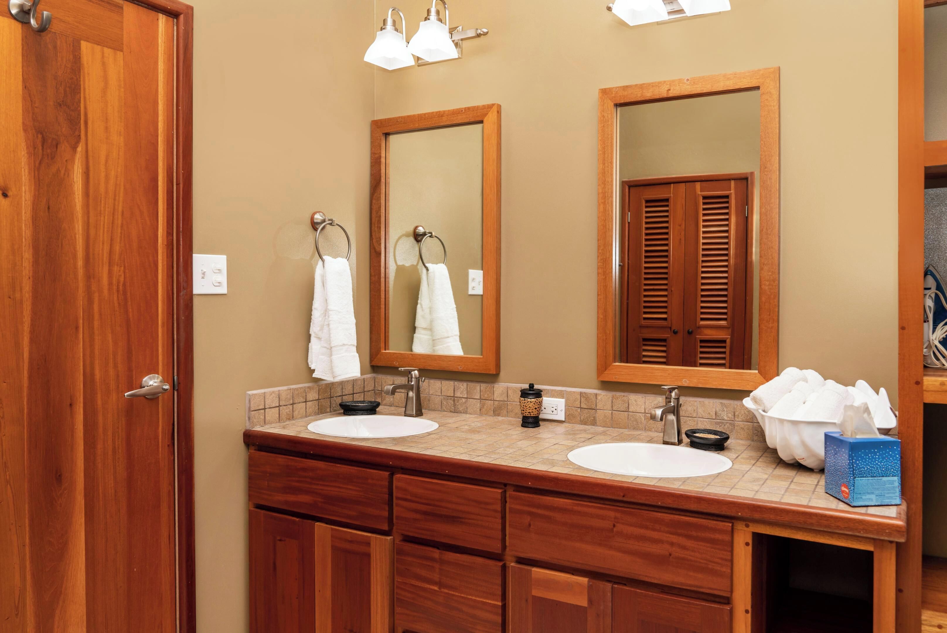 Une salle de bain avec deux lavabos, des meubles en bois, un porte-serviettes et un miroir.