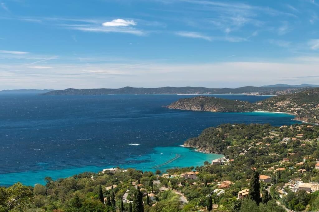 A coastal landscape with a view of the sea, a town, and distant hills.