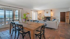 A spacious living room with a wooden dining table, black chairs, a sofa, and a fireplace.
