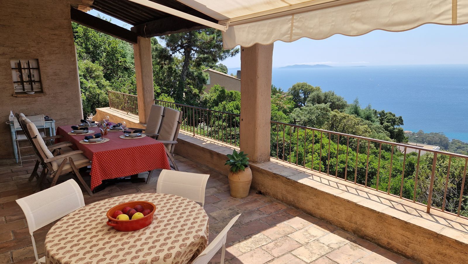 Una terrazza con un tavolo apparecchiato per mangiare, una sedia e un vaso con una pianta.