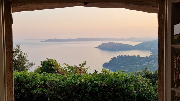 A view through an archway of a coastal landscape with distant mountains and a body of water.