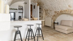 Cozinha acolhedora com arco de pedra, um sofá e dois bancos.