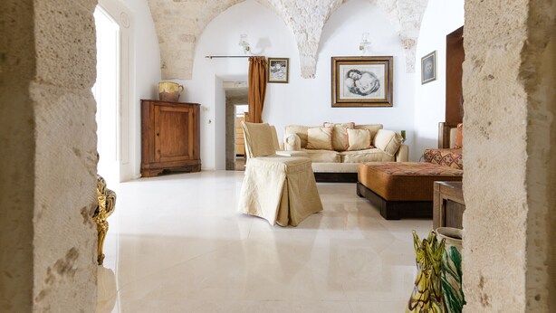 Uma sala de estar ampla com teto alto em arco, um conjunto de sofás, um armário de madeira e um quadro na parede.