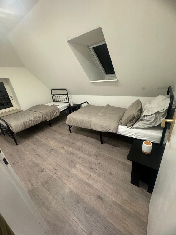 A dormitory room with two beds, a skylight, and a small window.
