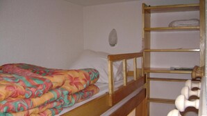 A bunk bed with a colorful bedspread, a wooden shelf unit with storage, and a small round mirror on the wall. - Ski-in/ski-out & foot of the slopes, 2nd floor, balcony, tv, ski locker, 19m², Samoëns (Samoëns)