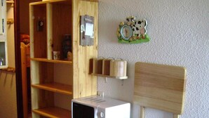 A compact living space with a wooden shelving unit, a microwave, a coffee maker, and a clock on the wall. - Ski-in/ski-out & foot of the slopes, 2nd floor, balcony, tv, ski locker, 19m², Samoëns (Samoëns)