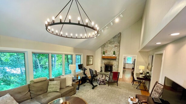 A spacious living area with a large sofa, a coffee table, and a fireplace. There are multiple windows providing a view of the outdoors. - Spacious home <1 min from Lincoln Peak! Fits the whole extended family (Warren)