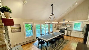 A modern kitchen with a central island, white cabinetry, and a view of the outdoors through large windows. - Spacious home <1 min from Lincoln Peak! Fits the whole extended family (Warren)