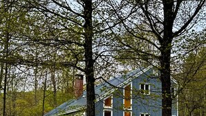 A two-story house with a gabled roof, surrounded by trees and a dirt path. - Spacious home <1 min from Lincoln Peak! Fits the whole extended family (Warren)