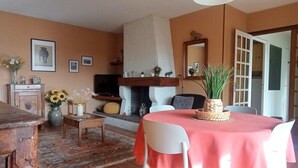 A living room with a fireplace, a dining table with chairs, and a TV.