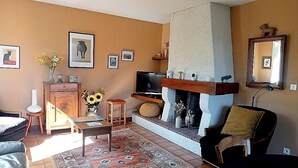 A living room with a fireplace, sofa, TV, and various decorations.