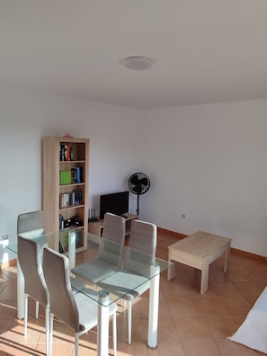 Cozy living space with a dining table, bookshelf, and flat-screen TV.