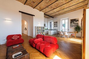 A spacious living area with a red sofa, a wooden coffee table, and a kitchen in the background. - Boho 202 - Two Bedroom Apartment, Sleeps 4 (Rome)