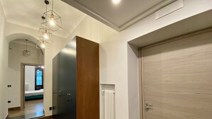 Un couloir moderne avec une porte en bois, un radiateur et un luminaire.