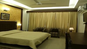 A hotel room with a large bed, two bedside tables, a desk, a chair, and a television. - Flamingo Tourist Resort (Hisar)