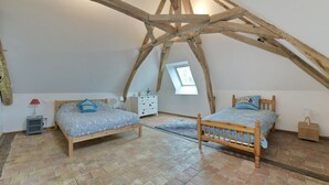 Ein Schlafzimmer mit zwei Holzbetten, einem Dachfenster und einem Fliesenboden.