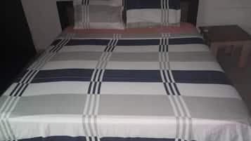 Una cama con un edredón a rayas, una almohada y una mesita de noche con una lámpara.