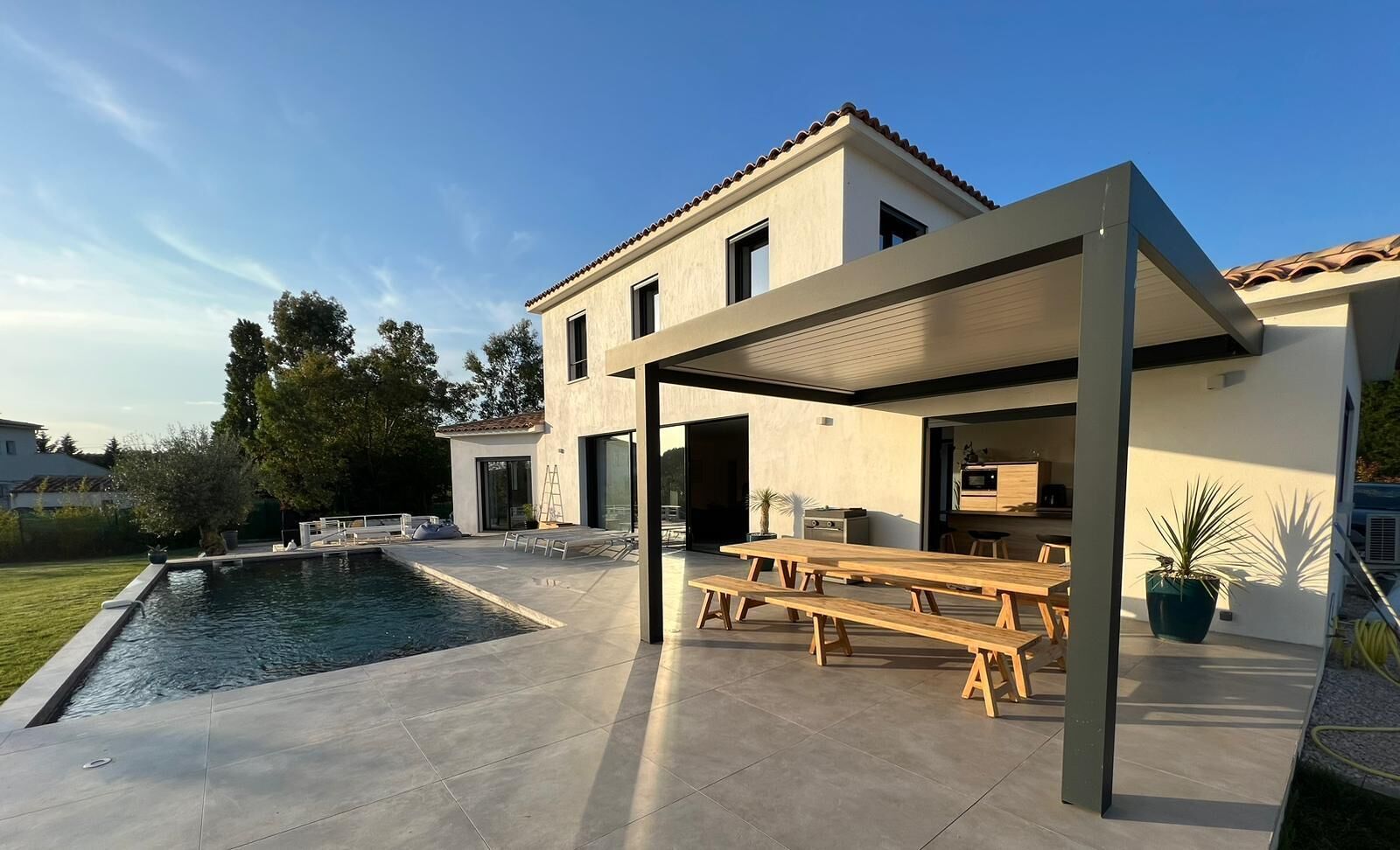 A modern house with a swimming pool, outdoor seating, and a patio area.