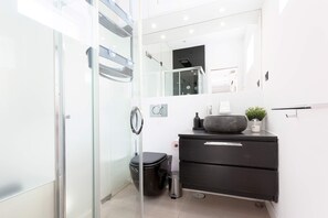 A modern bathroom with a glass shower enclosure, a black vanity with a bowl sink, and a mirror above the vanity. - Penthouse with terrace in Madrid. Delicias II (Madrid)