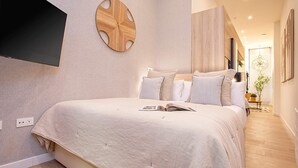 Une chambre moderne avec un grand lit, un téléviseur fixé au mur et une décoration murale en bois.