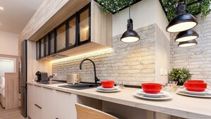 Une cuisine moderne avec un mur de crédence en pierre, des armoires en bois et un coin bar agrémenté de bols rouges.