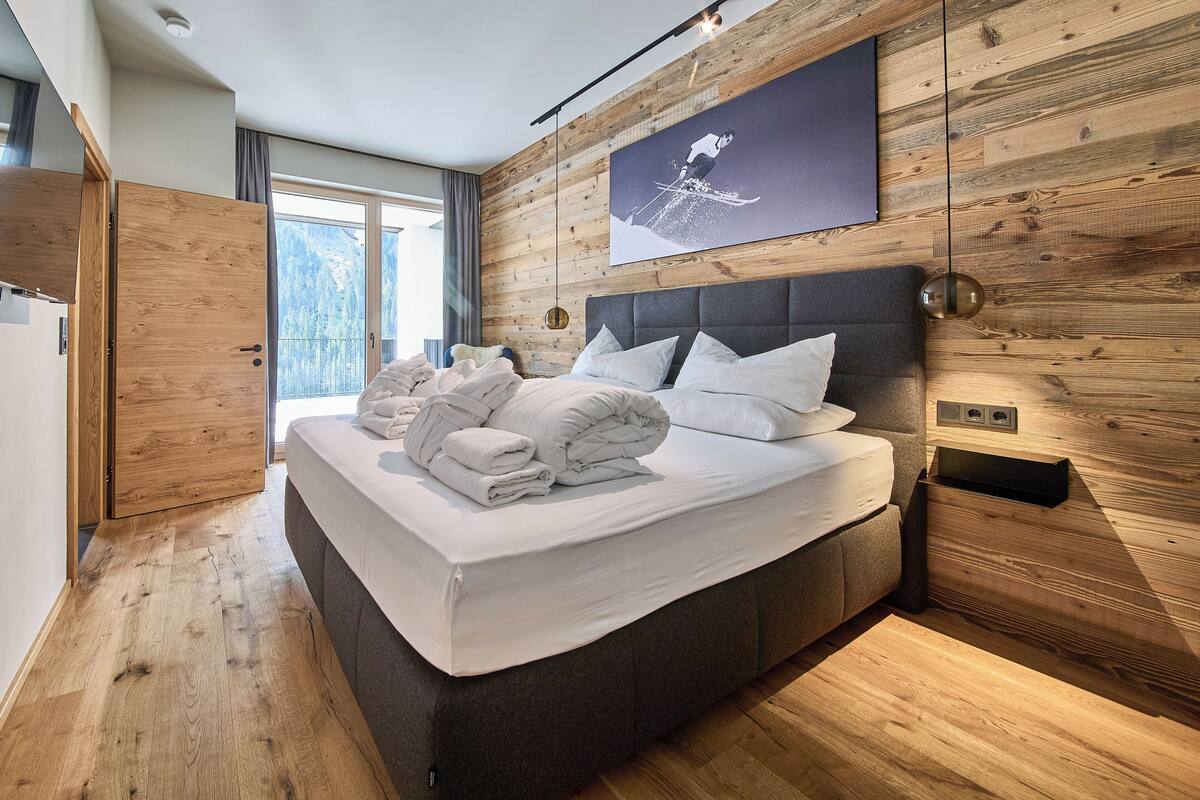 Un dormitorio moderno con una cama grande, paredes de madera y una obra de arte con temática de esquí.