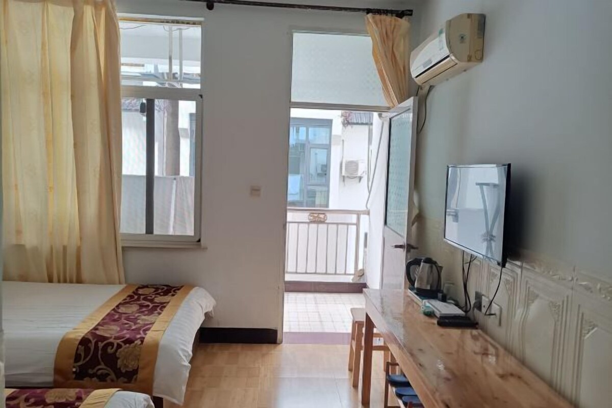 Ein Hotelzimmer mit Bett, Schreibtisch, Fernseher und einem Balkon.