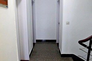 Un estrecho pasillo con piso alfombrado y barandilla a la derecha.