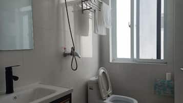 Ein Badezimmer mit Waschbecken, Toilette und Dusche. Ein Fenster sorgt für natürliches Licht.