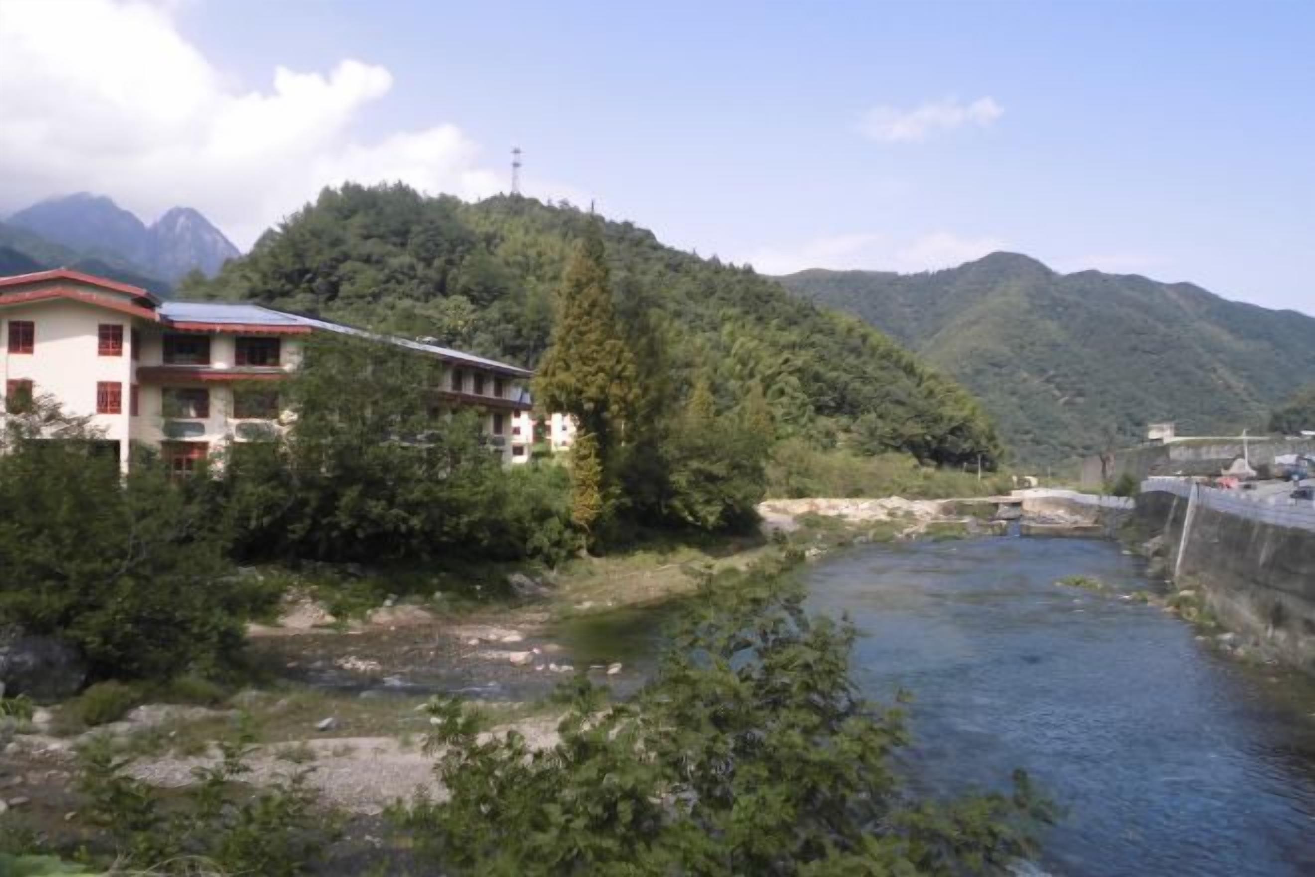 Un edificio con tejado rojo, un río y montañas al fondo.
