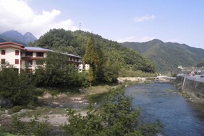 A building with a red roof, a river, and a mountainous backdrop. - Mount Huangshan Jiayuan Inn (Huangshan City)