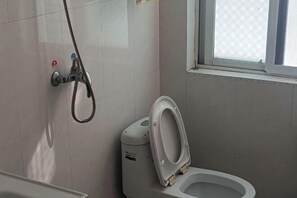 Ein Badezimmer mit Toilette, Duschkopf und Fenster.