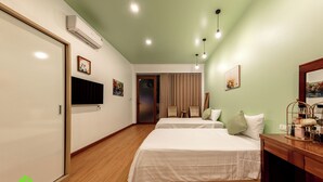 A hotel room with two beds, a wooden floor, a flat-screen TV, a desk with a mirror, and a window with curtains. - Room in House - Trang An Ao Dai Homestay - Family Room With Field View and Private Bathroom (Ninh Binh)