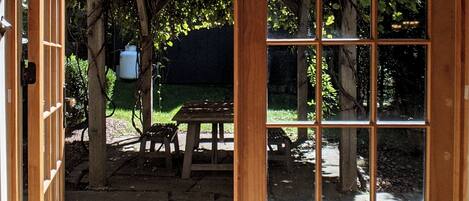 Eine Holztür, die in einen Garten mit Picknicktisch und einer Pergola führt.